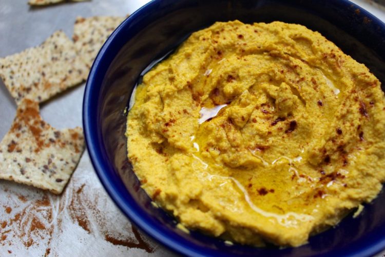 bowl of paleo pumpkin hummus surrounded by crackers